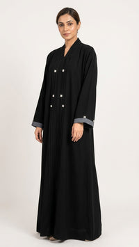 Black abaya with grey cuff trim worn by a model in a studio setting