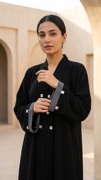 Close view of black abaya front pleats, grey cuffs and square embellishment details
